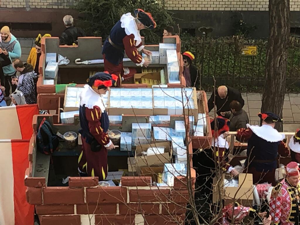 Auf dem Mainzer Karnevalsumzug werden von kostümierten Personen Schachteln mit FFP 2 masken verteilt.