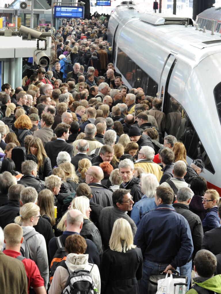 Ein ICE, ein völlig überfüllter Bahnsteig und über den Menschen eine Überwachungskamera